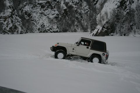 1990 Chevrolet Suburban - A white Jeep Wrangler navigates a snowy landscape, its brown hardtop contrasting with the white exterior.