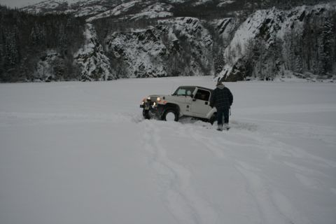 1990 Chevrolet Suburban - A white Jeep Wrangler is stuck in deep snow with a person standing next to it, surrounded by a winter landscape.