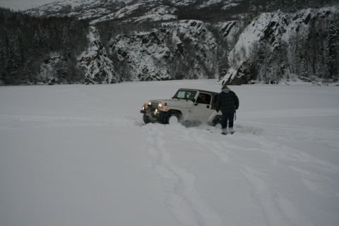 1990 Chevrolet Suburban - A white Jeep Wrangler struggles to move through deep snow near a snow-covered mountainside.