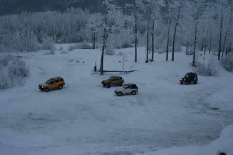 1990 Chevrolet Suburban - Multiple SUVs navigate a snowy landscape with frosted trees.