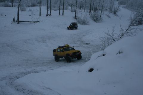 1990 Chevrolet Suburban - Two SUVs navigate a snow-covered landscape with trees in the background.