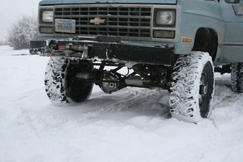 1990 Chevrolet Suburban - This 1990 Chevrolet Suburban's front end is visible, covered in snow, with large tires and a winch mounted on the bumper.
