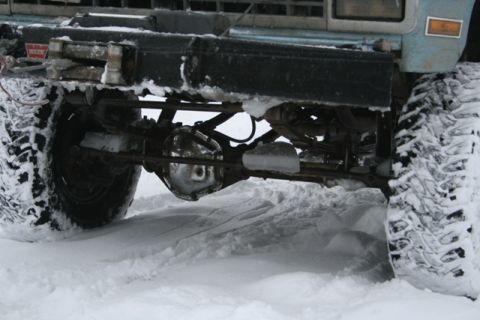 1990 Chevrolet Suburban - Vehicle's front axle and suspension system are visible in a snowy environment, with a winch mounted on the bumper.