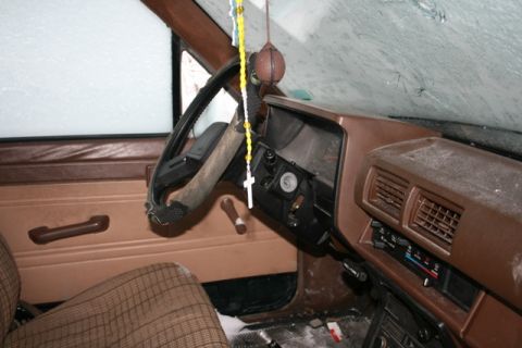 1990 Chevrolet Suburban - The interior of a vehicle, covered in dust, with a rosary hanging from the mirror.
