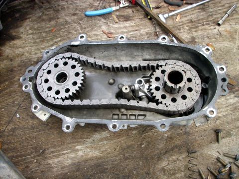 1992 Ford Bronco - A disassembled transfer case, revealing its internal chain and gear mechanism. Text on a sprocket reads 'REAR'.