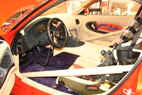 Interior of a race car with roll cage, racing seat, and custom dashboard