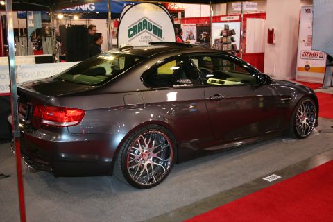 Dark grey BMW M3 coupe with custom chrome wheels, seen from the rear quarter