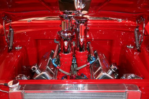 Custom engine bay with chrome dual carburetors and red engine components. Radiator visible at the bottom