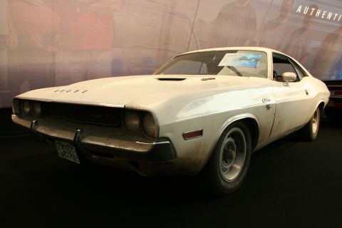 White Dodge Challenger with a hood scoop and chrome bumper, viewed from the front three-quarter angle