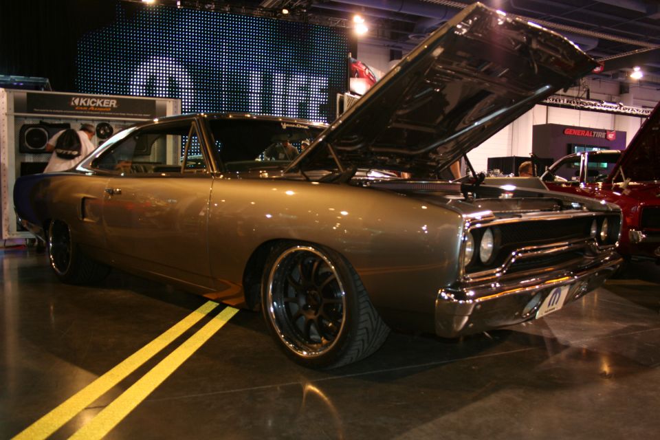 1969 Plymouth Road Runner with hood open, custom wheels, and a red car behind it