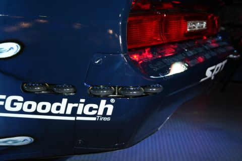 Blue race car rear with BFGoodrich Tires logo and red taillight. Some text is reflected on the panel