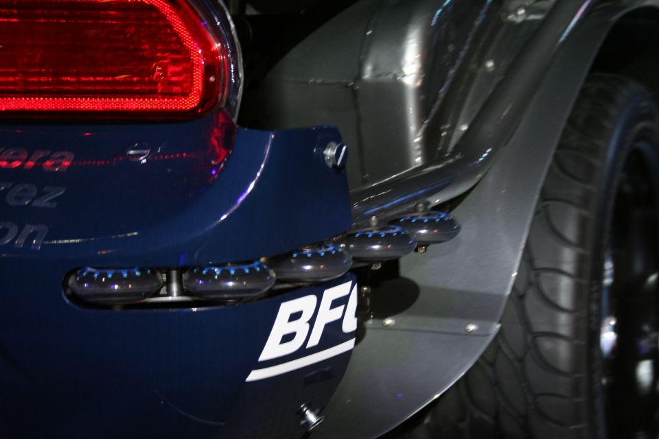 Dark blue car rear bumper with four exhaust pipes, BFI logo, and tire visible