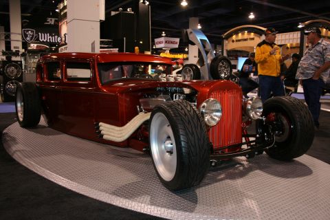 Red hot rod with exposed engine and side pipes, on display