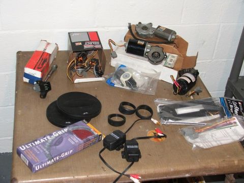 1989 Ford Bronco II - Various automotive parts are laid out on a table, including motors and a steering wheel cover.