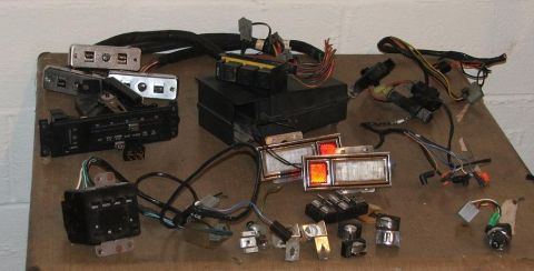 1989 Ford Bronco II - A collection of automotive electrical components and lighting parts are displayed on a wooden surface.