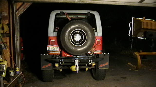 1989 Jeep YJ rear view showing spare tire on swing away bumper, 4x4 mud flaps, and tow hitch