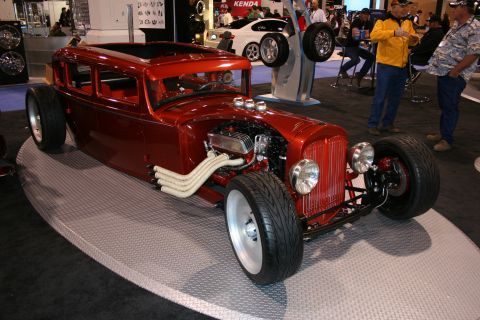 Red hot rod with exposed engine, custom exhaust pipes, and wide tires on display