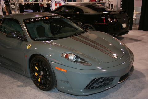 Gray Ferrari F430 with racing stripes and a black Nissan GT-R behind it