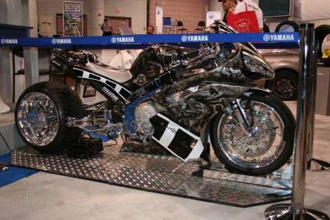 Custom motorcycle with elaborate airbrushed graphics and chrome wheels, displayed indoors