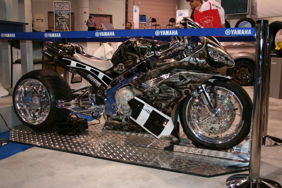 Custom motorcycle with elaborate airbrushed graphics and chrome wheels, displayed indoors