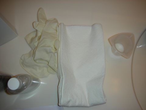 1998 Ford Crown Victoria - A pair of yellow medical gloves and a folded white cloth are laid out on a white surface, possibly for a cleaning or medical procedure.