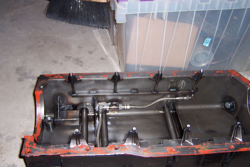 Oil pan with internal baffles and oil pickup tube, showing welds and orange gasket material