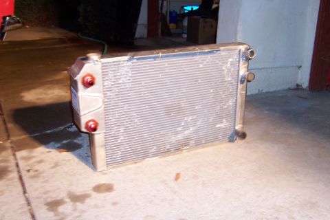 1971 Ford Mustang - A radiator with red caps and aluminum tanks sits on a concrete surface, possibly for a vehicle build or repair.