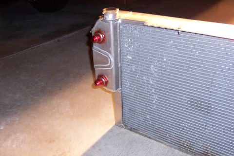 1971 Ford Mustang - This is a close-up view of a car radiator, showing its metallic fins and red inlet/outlet ports.