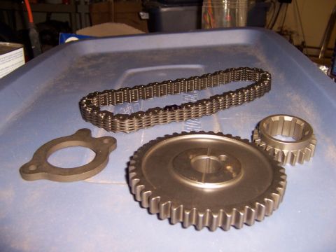 1971 Ford Mustang - A set of engine timing components, including a chain, gears, and a gasket, are laid out on a blue surface.