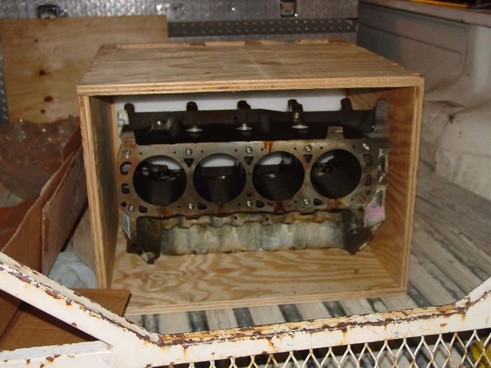 Engine block sitting in a wooden crate inside a vehicle
