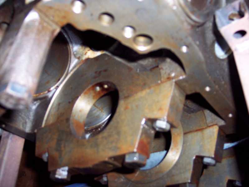 Engine block with main bearing caps installed, showing rust and wear