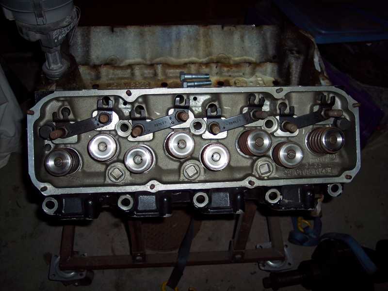 Engine cylinder head on stand with visible rocker arms and valves