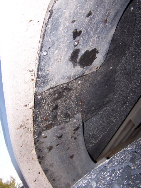1986 Ford Bronco - The interior of a vehicle's wheel well shows accumulated dirt and moisture.