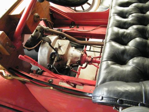 1909 Ford Model T - The intricate mechanical workings and tufted upholstery of an old automobile are visible.