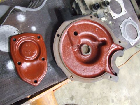 1967 Ford Bronco - Two engine components, likely from a vehicle, are laid out on a workbench for inspection or repair.