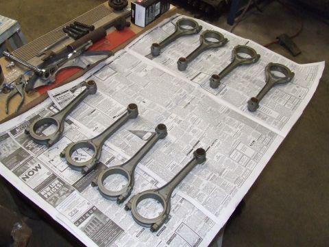1967 Ford Bronco - Several engine connecting rods are arranged on a surface covered with newspaper pages, likely for a repair or rebuild project.