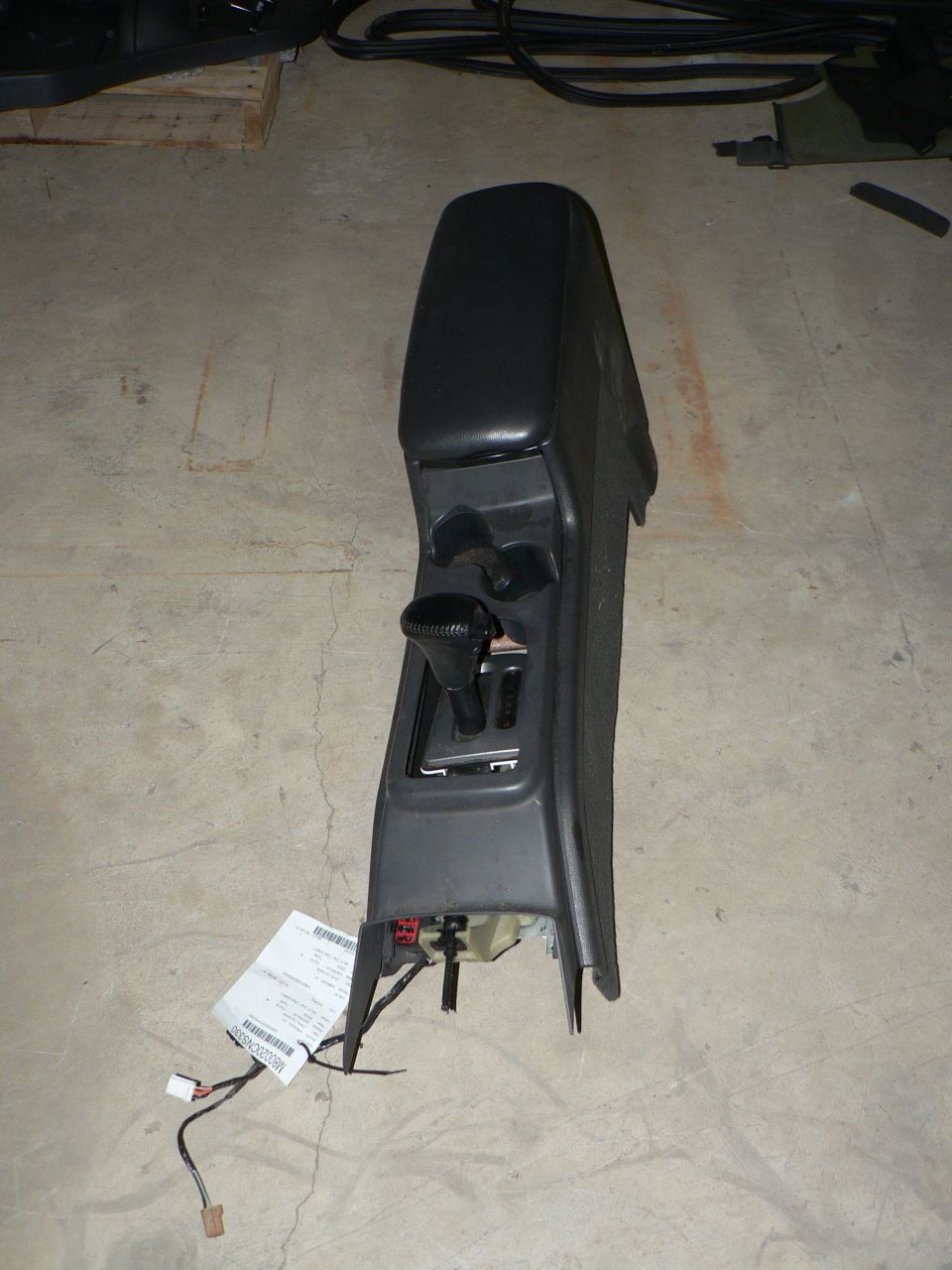 Car center console with automatic gear shifter and storage compartment. Wiring harness attached