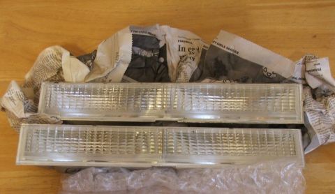 1989 Ford Bronco II - A pair of clear parking lights are shown, wrapped in newspaper on a wooden surface.