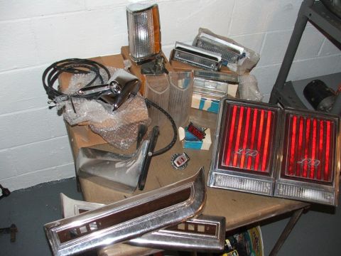 1989 Ford Bronco II - Various car parts are laid out on a table, including tail lights, a side mirror, and trim pieces.
