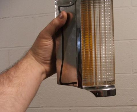 1989 Ford Bronco II - A hand holds an amber turn signal lens with chrome trim, likely a replacement part.