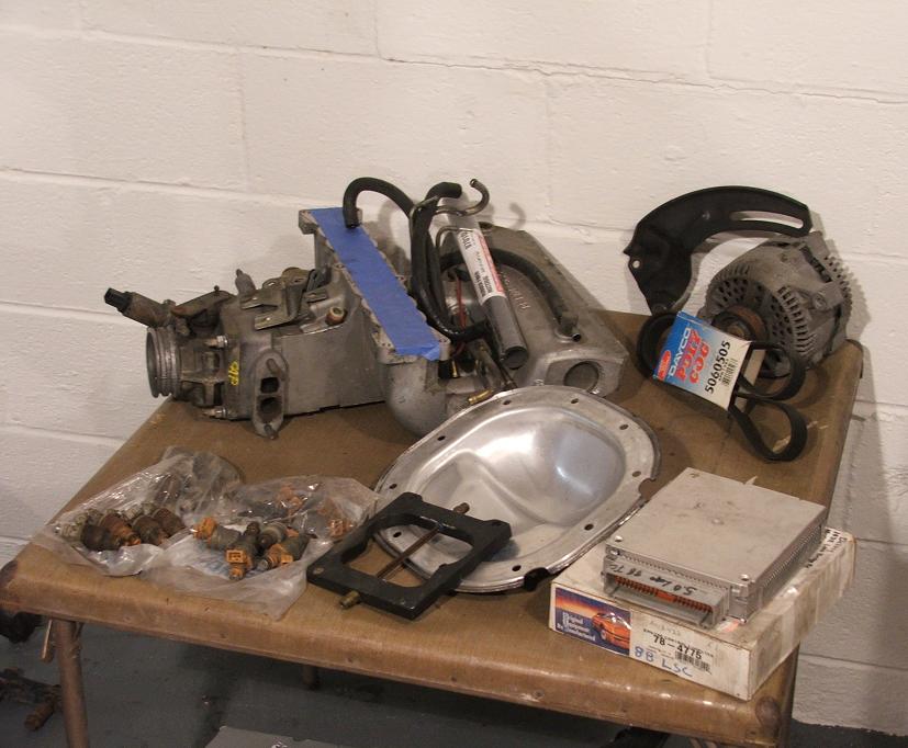 Carburetor, fuel injectors, alternator, and ECU on a table