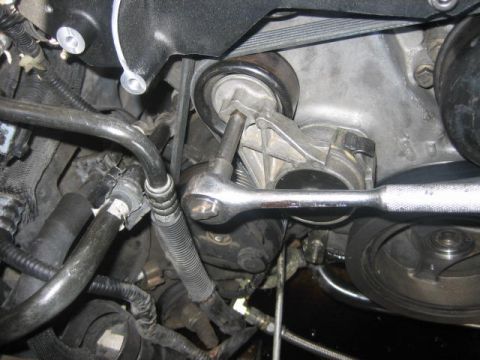 1996 Ford Thunderbird - A mechanic uses a wrench to adjust the engine belt tensioner on a vehicle.