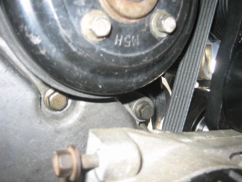 1996 Ford Thunderbird - A close-up view of the serpentine belt and pulleys within a vehicle's engine compartment.