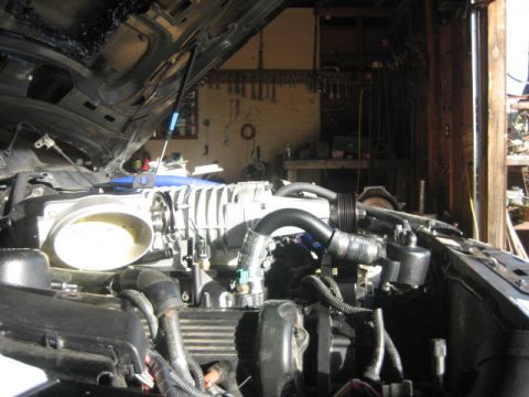 1996 Ford Thunderbird - The engine bay of a vehicle is shown with a supercharger installed.
