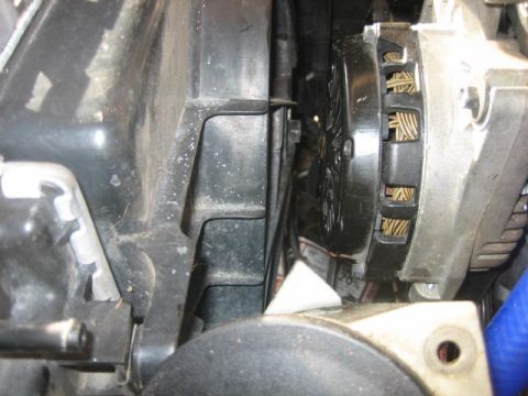 1996 Ford Thunderbird - Close-up view of an alternator and fan shroud within a vehicle's engine compartment.