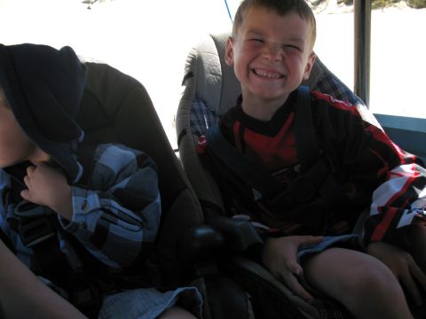 1976 Ford Bronco - Two children are buckled into car seats inside a vehicle on a sunny day.
