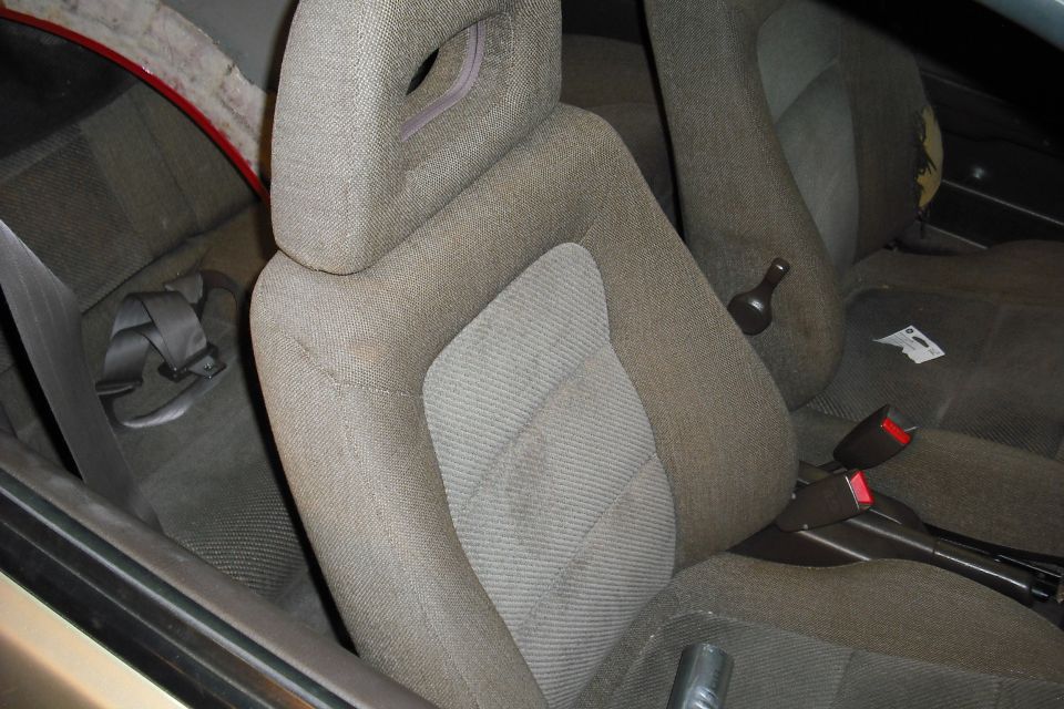 Worn tan cloth front bucket seat inside a car