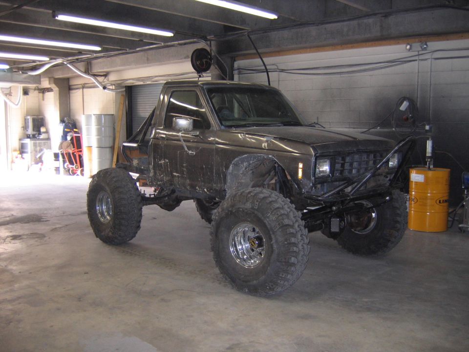 Dark gray lifted Ford SUV on mud tires and chrome wheels parked in a shop