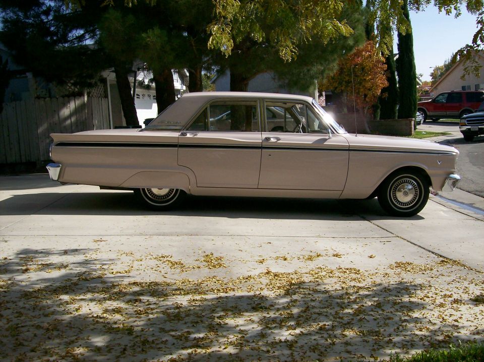 Side view of a beige 1963 Ford Fairlane four-door sedan on a leaf-covered driveway