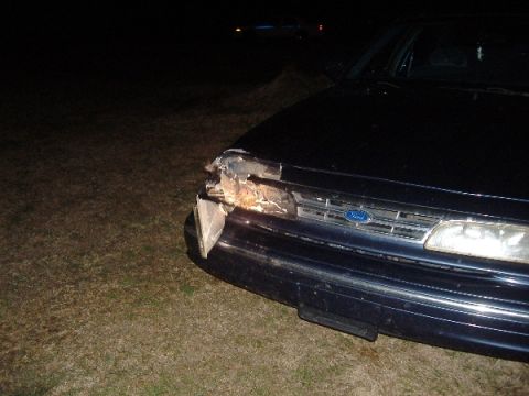 1997 Ford Crown Victoria - A dark blue 1997 Ford Crown Victoria shows significant damage to its front right headlight and grille.